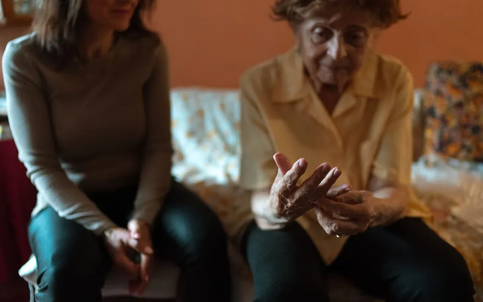 Caregiver and older woman talking together on a couch